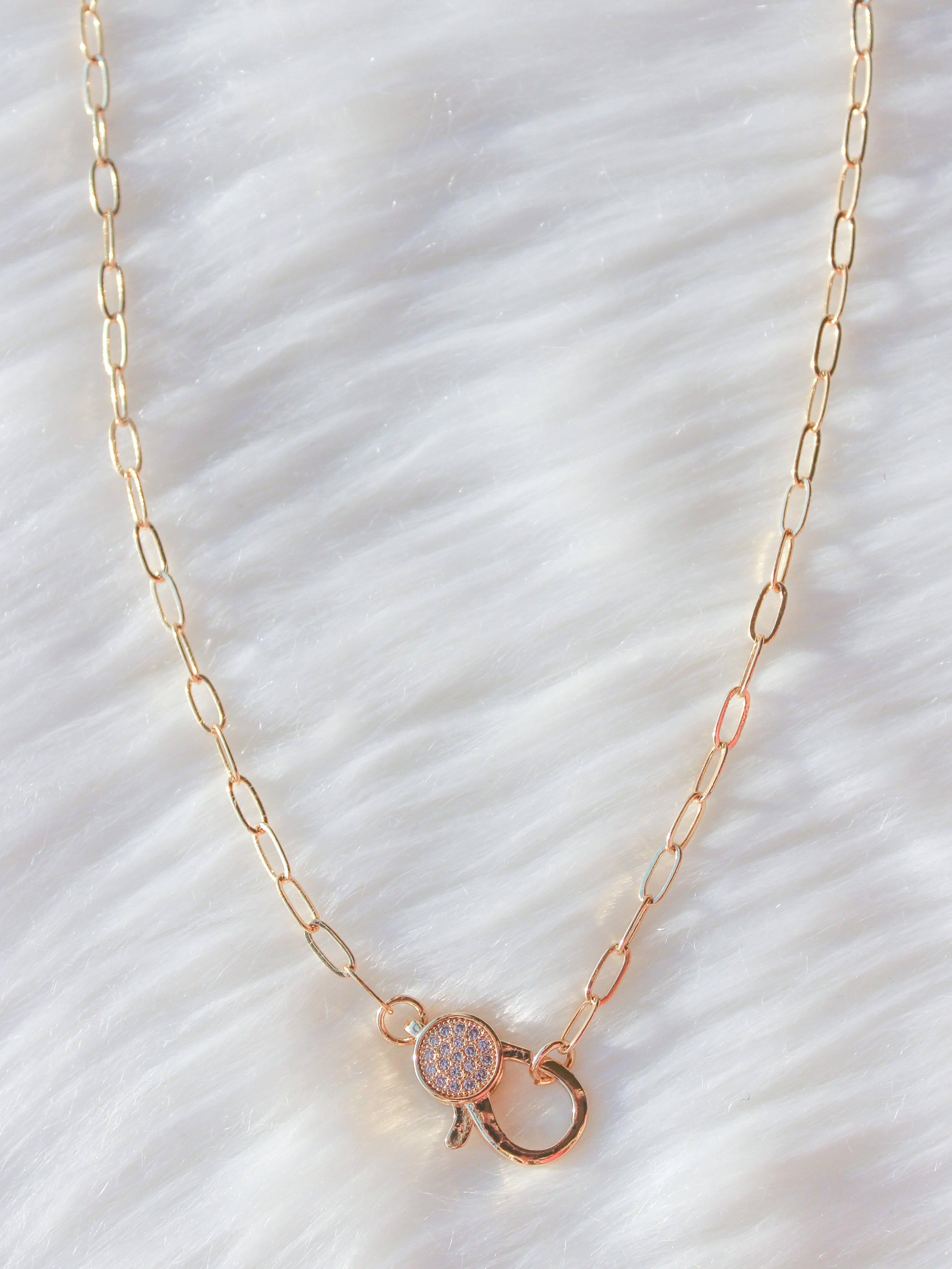 A 42-inch long gold-colored chain link necklace with no clasp. All of the  links are approximately the same size and are slightly concave in shape.  Each link has a visible soldered seam.